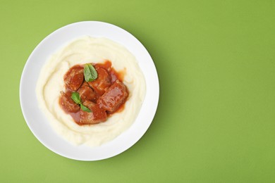Delicious goulash with mashed potato on green background, top view. Space for text