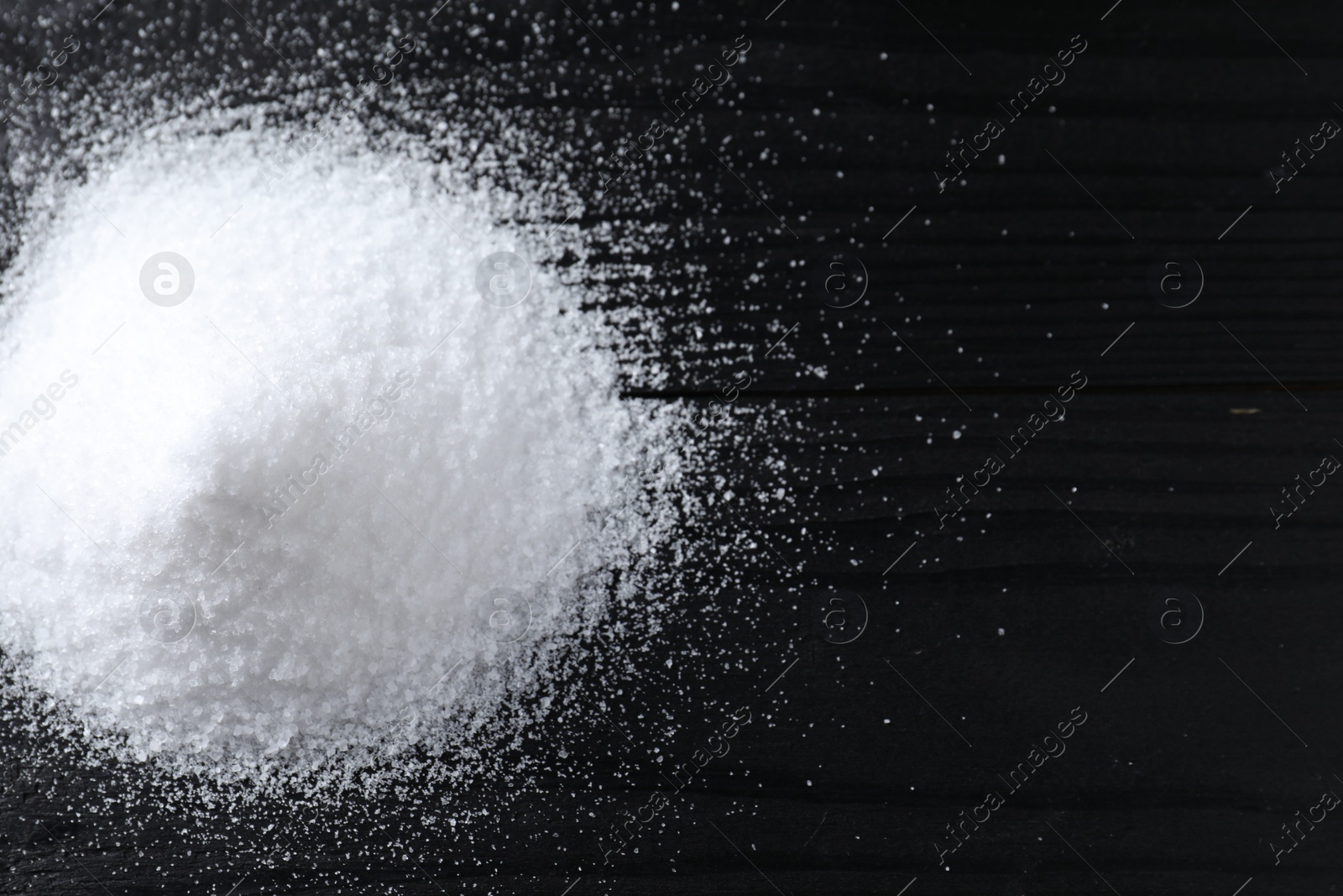 Photo of Pile of organic salt on black wooden table, top view. Space for text