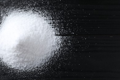 Photo of Pile of organic salt on black wooden table, top view. Space for text