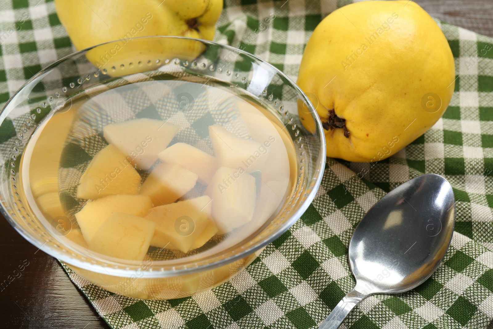 Photo of Delicious quince drink in glass bowl, fresh fruits and spoon on table, closeup