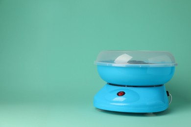 Portable candy cotton machine on turquoise background, space for text
