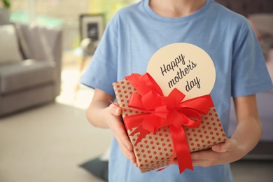 Photo of Little child with gift box for Mother's Day at home