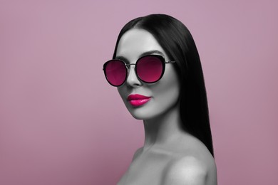 Attractive woman in stylish sunglasses on pink background. Color accent