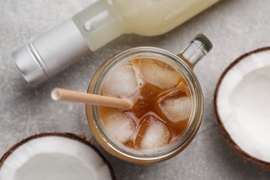 Mason jar of delicious iced coffee with coconut syrup on light grey table, flat lay