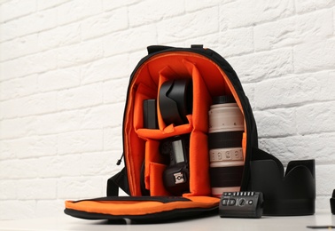 Backpack with professional photographer's equipment on table indoors