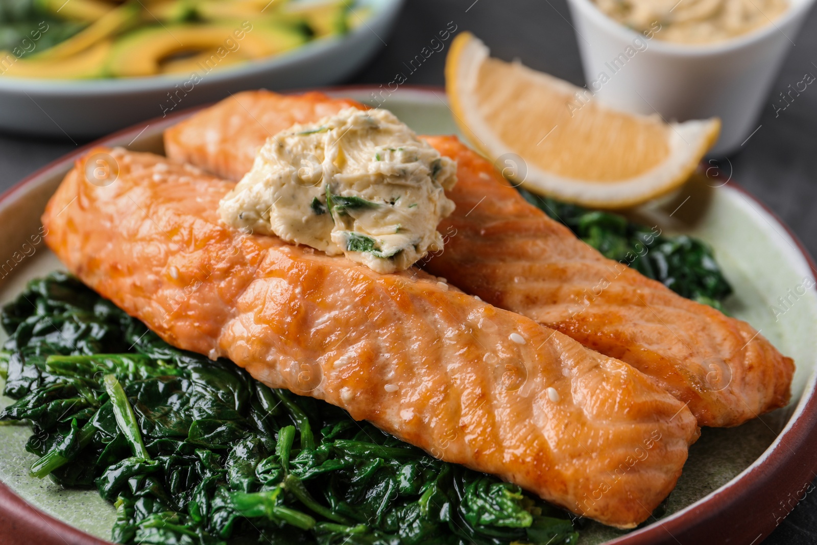 Photo of Tasty salmon with spinach on plate, closeup