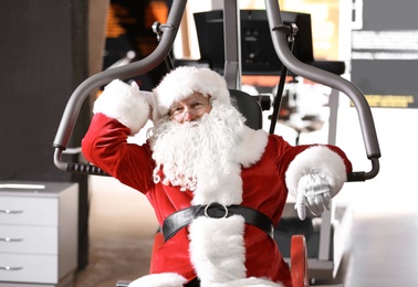 Photo of Authentic Santa Claus resting after exercise in modern gym