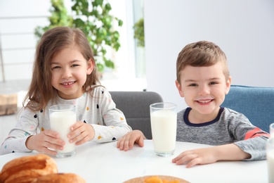 Cute little kids having breakfast with milk at table