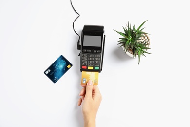 Woman using modern payment terminal on white background, top view