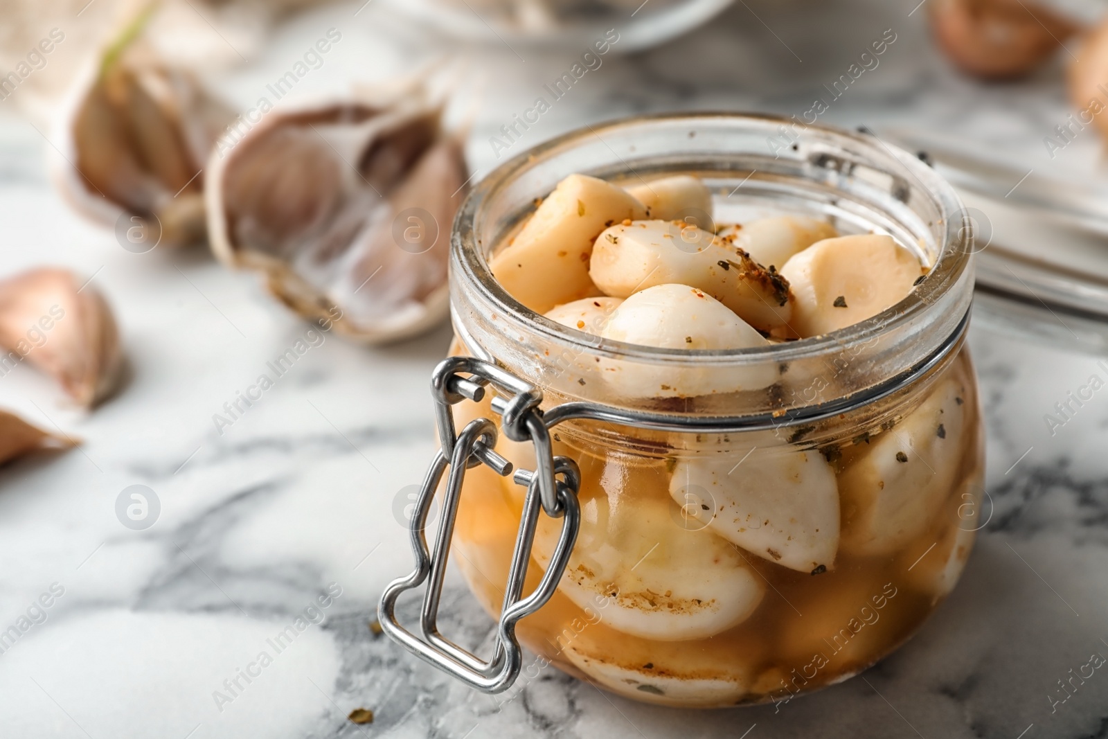 Photo of Preserved garlic in glass jar on table, closeup. Space for text