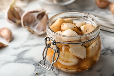 Photo of Preserved garlic in glass jar on table, closeup. Space for text