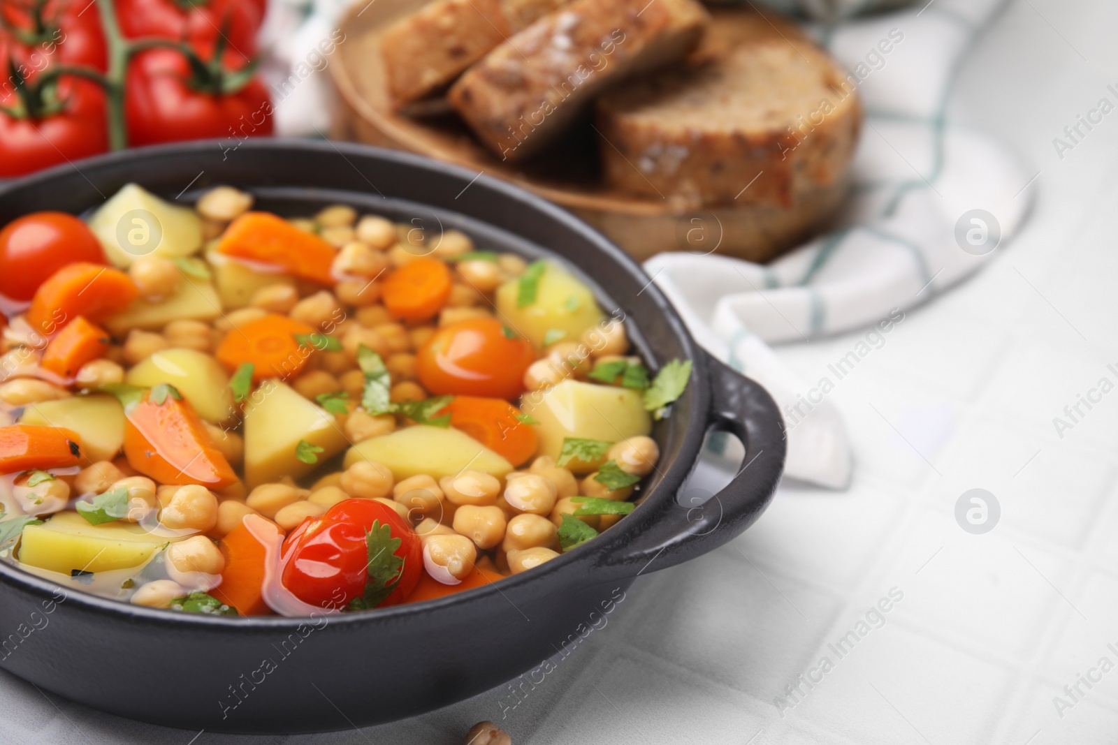 Photo of Tasty chickpea soup on white tiled table, closeup