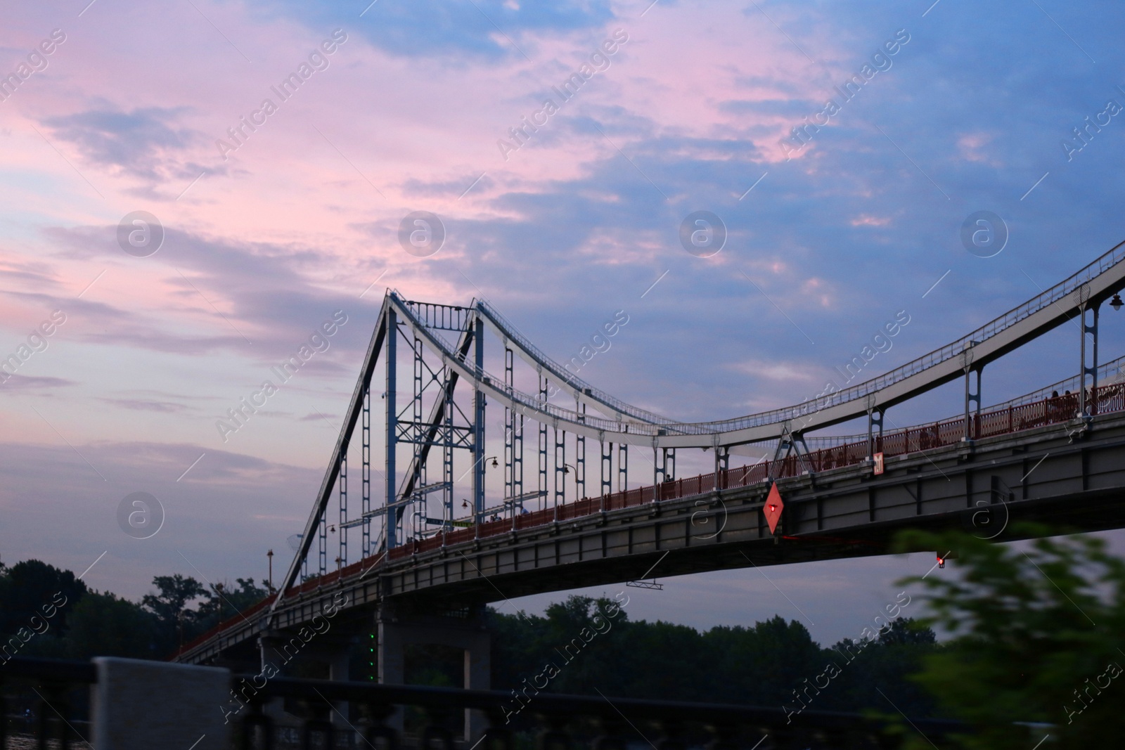 Photo of KYIV, UKRAINE - MAY 23, 2019: Beautiful view of pedestrian bridge over Dnipro river in evening