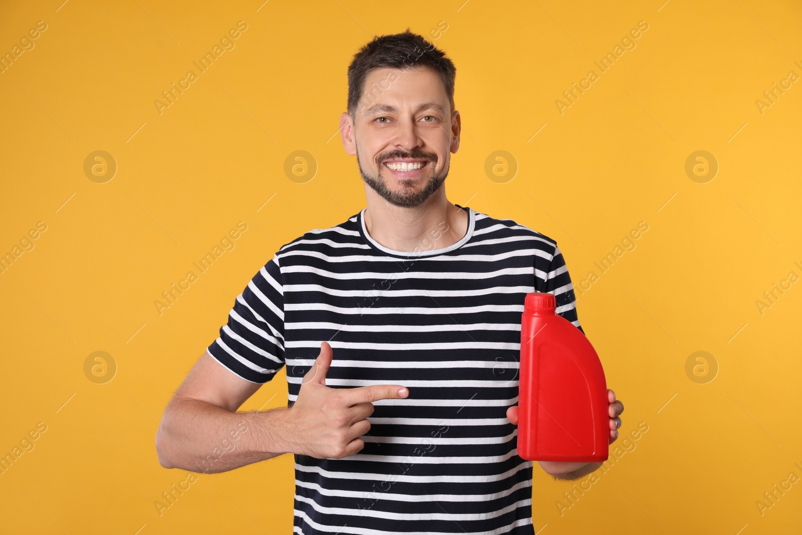 Photo of Man pointing at red container of motor oil on orange background