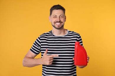 Man pointing at red container of motor oil on orange background