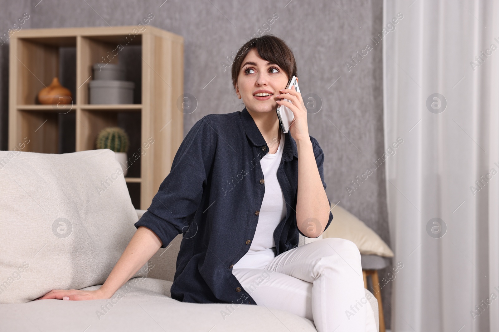 Photo of Beautiful young housewife talking on smartphone at home