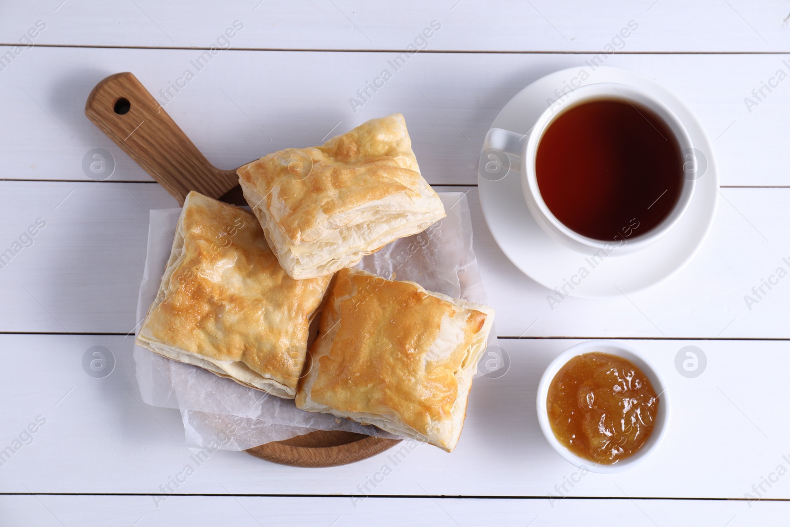 Photo of Delicious puff pastry served on white wooden table, flat lay