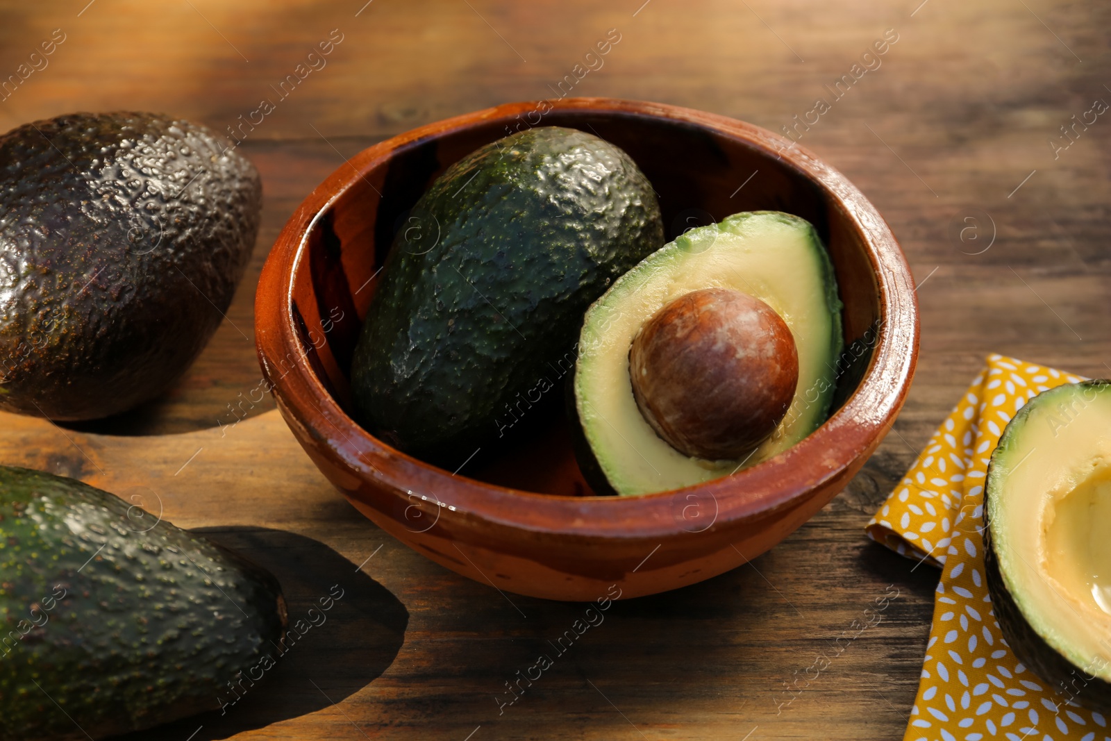 Photo of Tasty fresh avocados in bowl on wooden table