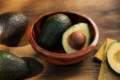 Photo of Tasty fresh avocados in bowl on wooden table
