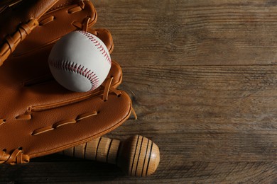 Photo of Baseball glove, bat and ball on wooden table, closeup. Space for text