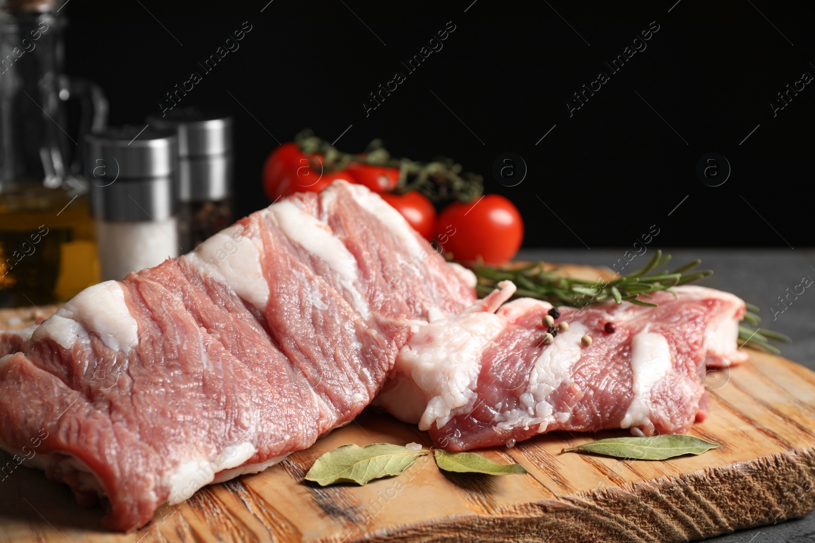 Photo of Raw ribs with bay leaves and pepper on wooden board, closeup