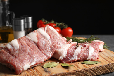 Raw ribs with bay leaves and pepper on wooden board, closeup