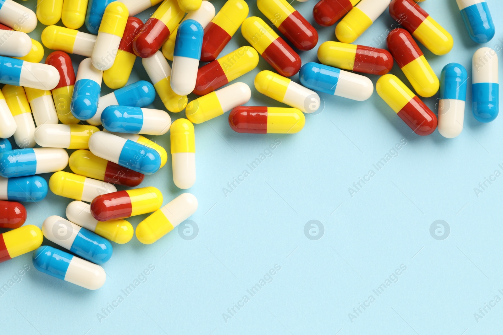 Photo of Many antibiotic pills on light blue background, top view. Space for text