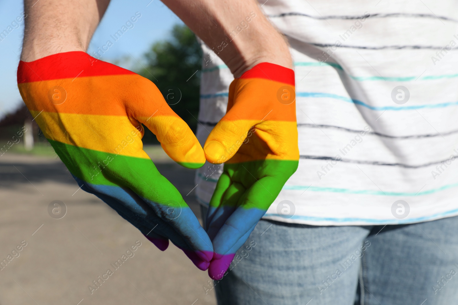 Image of Gay couple forming heart with hands in park, closeup