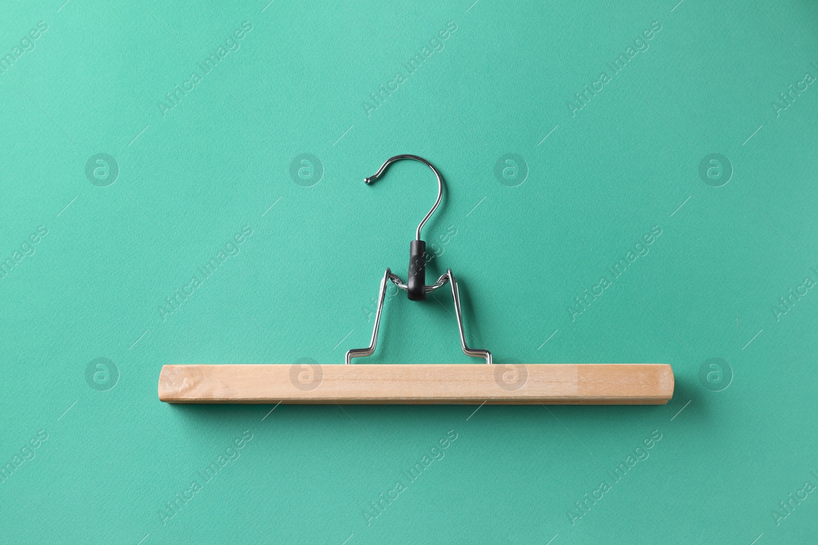 Photo of One wooden hanger on dark turquoise background, top view