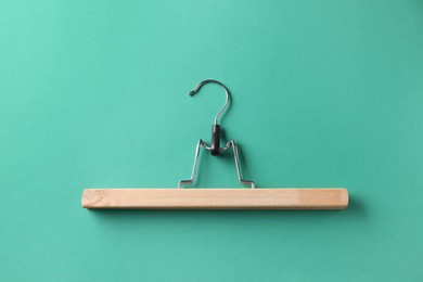 One wooden hanger on dark turquoise background, top view