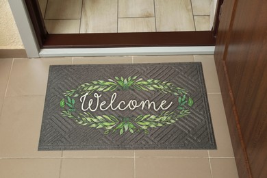 Photo of Beautiful doormat with word Welcome on floor near entrance, above view