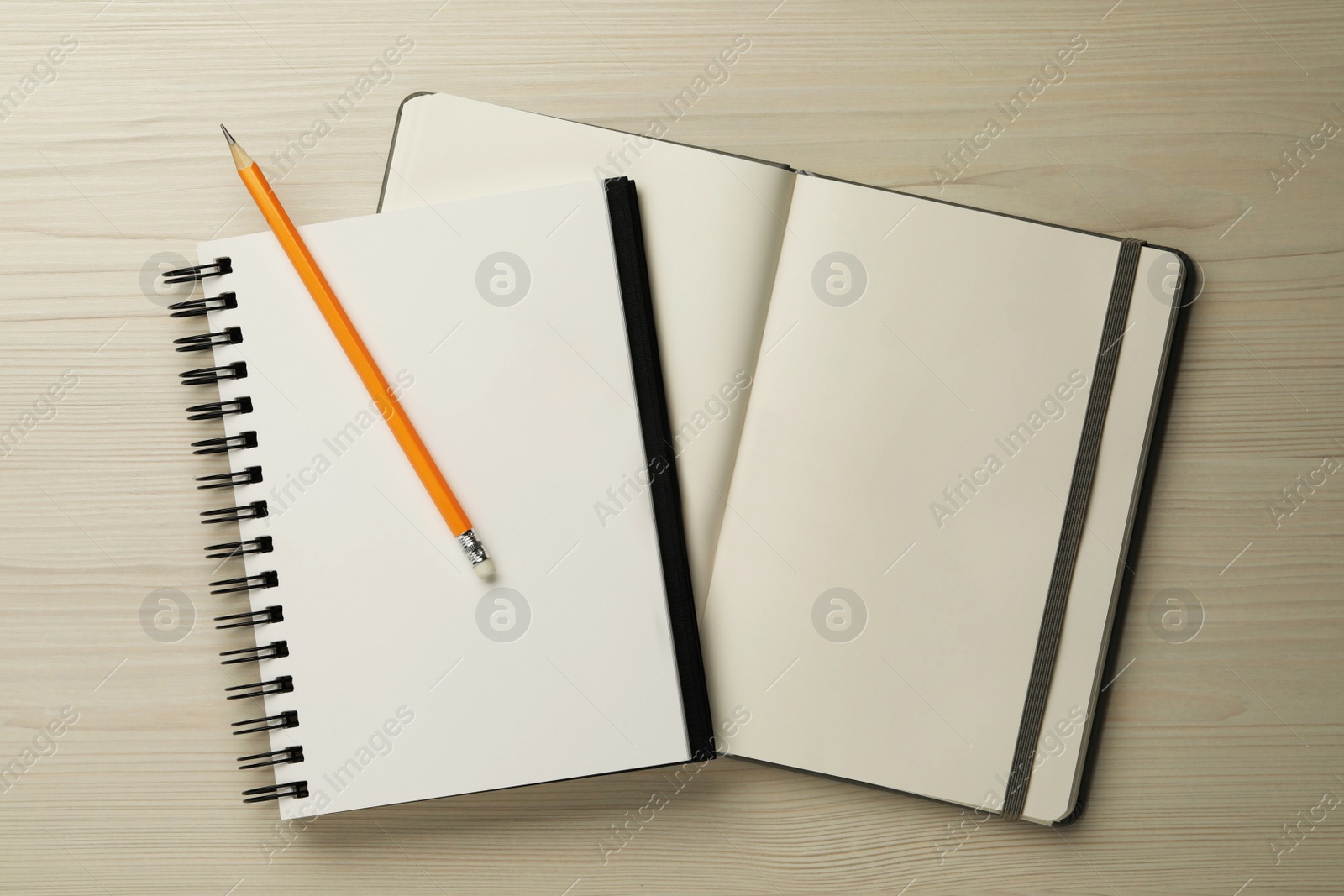 Photo of Notebooks and pencil on white wooden table, top view