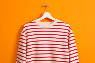 Hanger with striped sweatshirt on orange wall