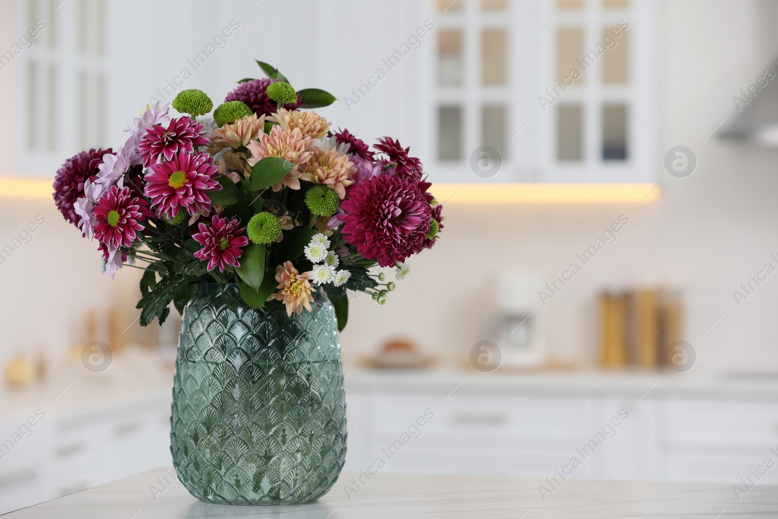 Photo of Bouquet of beautiful chrysanthemum flowers on table in kitchen, space for text