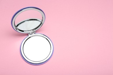 Photo of Stylish cosmetic pocket mirror on pink background, top view. Space for text