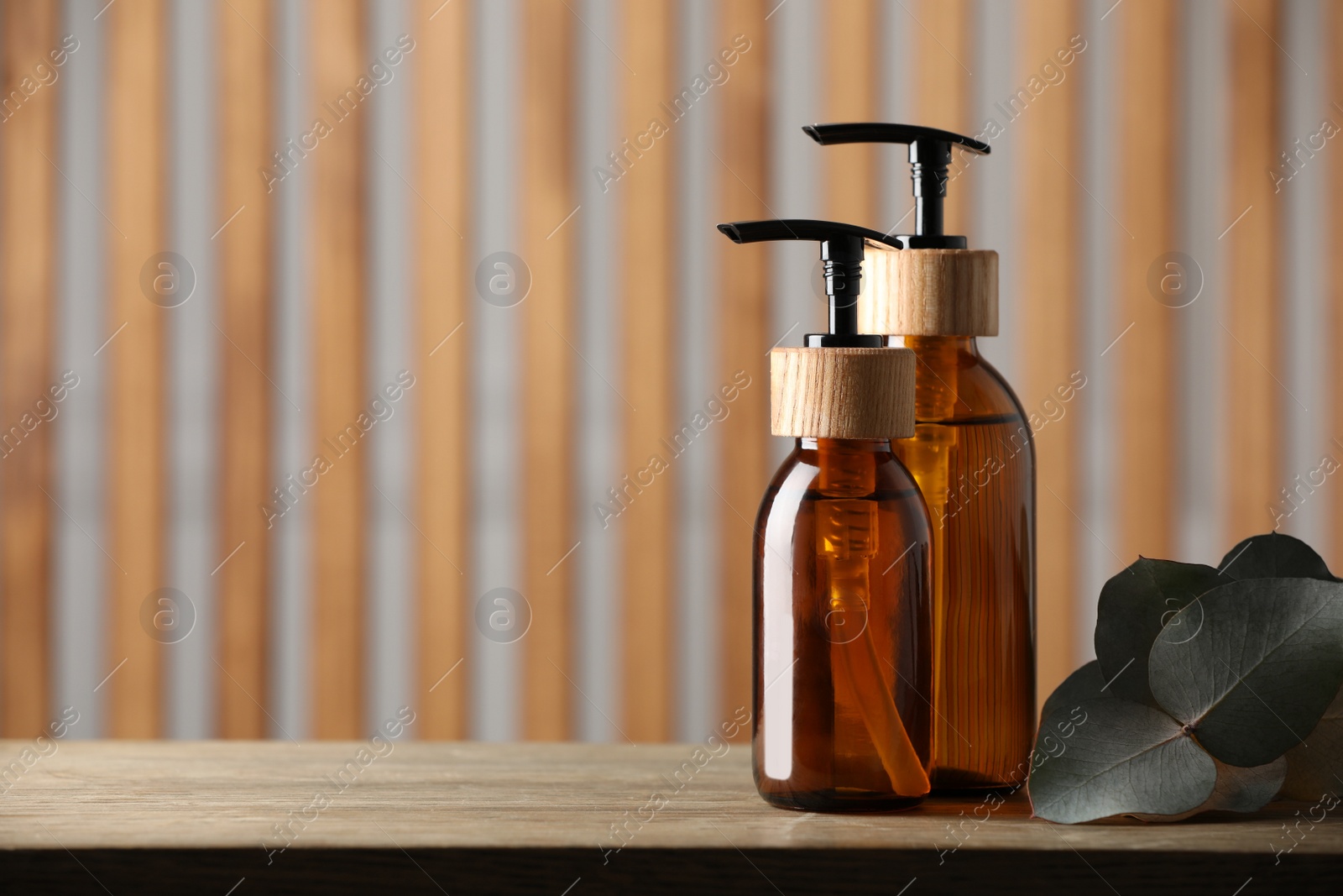 Photo of Bottles with dispenser caps on wooden table indoors. Space for text
