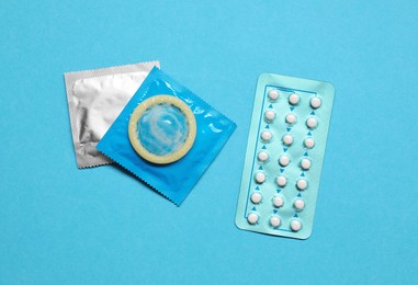 Photo of Contraception choice. Pills and condoms on light blue background, flat lay