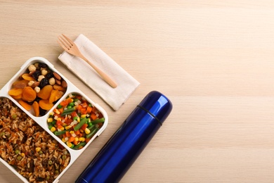 Thermos and lunch box with food on wooden background, flat lay. Space for text