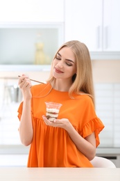 Photo of Young woman with yogurt in kitchen