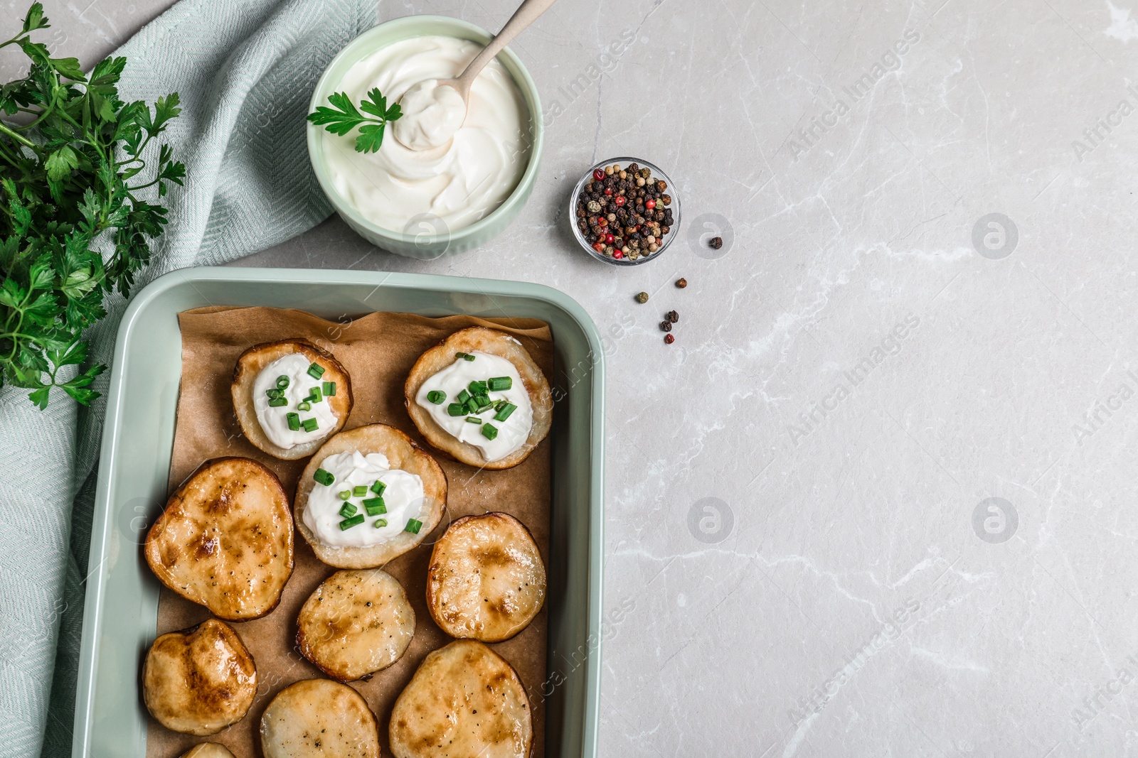 Photo of Sour cream dressing and delicious potato wedges on light grey table, flat lay