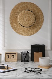 Stylish office workplace. Decor elements, glasses, cup and stationery on marble table near white wall