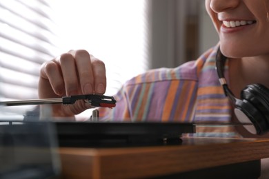 Photo of Young woman using turntable at home, closeup