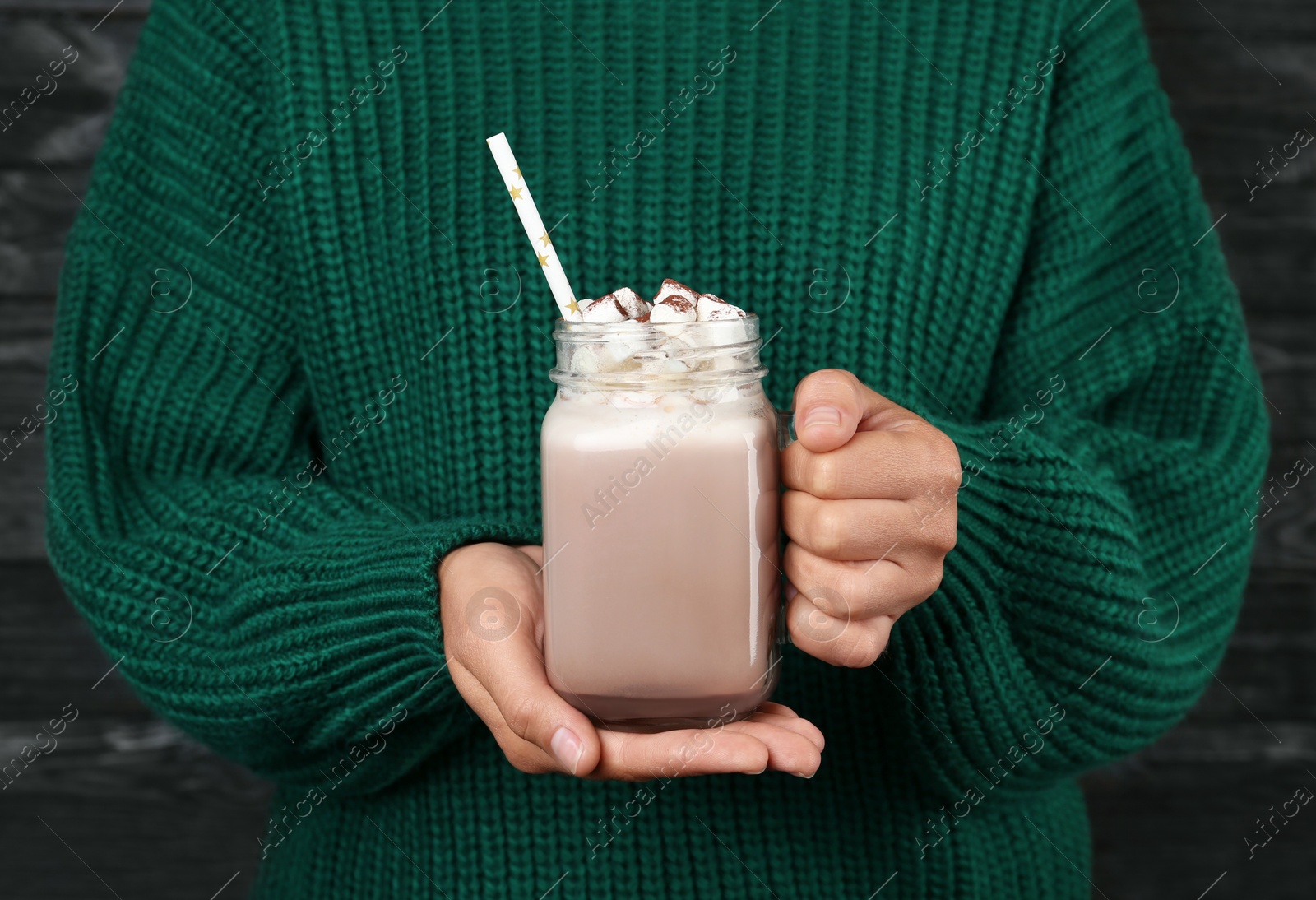 Photo of Woman holding mason jar of delicious cocoa drink with marshmallows, closeup