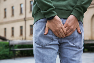 Man suffering from hemorrhoid pain outdoors, back view