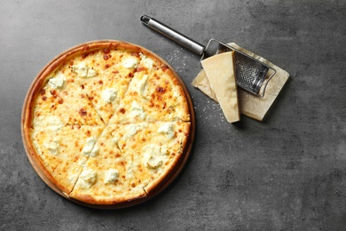 Tasty hot pizza, cheese and grater on grey background, top view