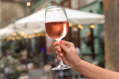 Photo of Woman holding glass of rose wine outdoors, closeup