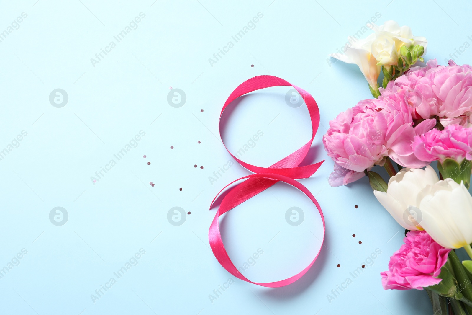 Photo of 8th of March greeting card design with pink ribbon, beautiful flowers and space for text on light blue background, flat lay. International Women's day