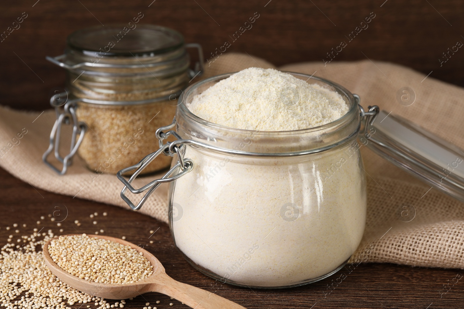 Photo of Jar with quinoa flour and seeds on wooden table