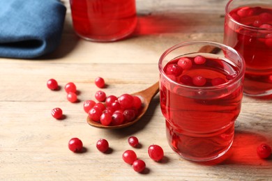 Tasty cranberry juice in glasses and fresh berries on wooden table, closeup. Space for text