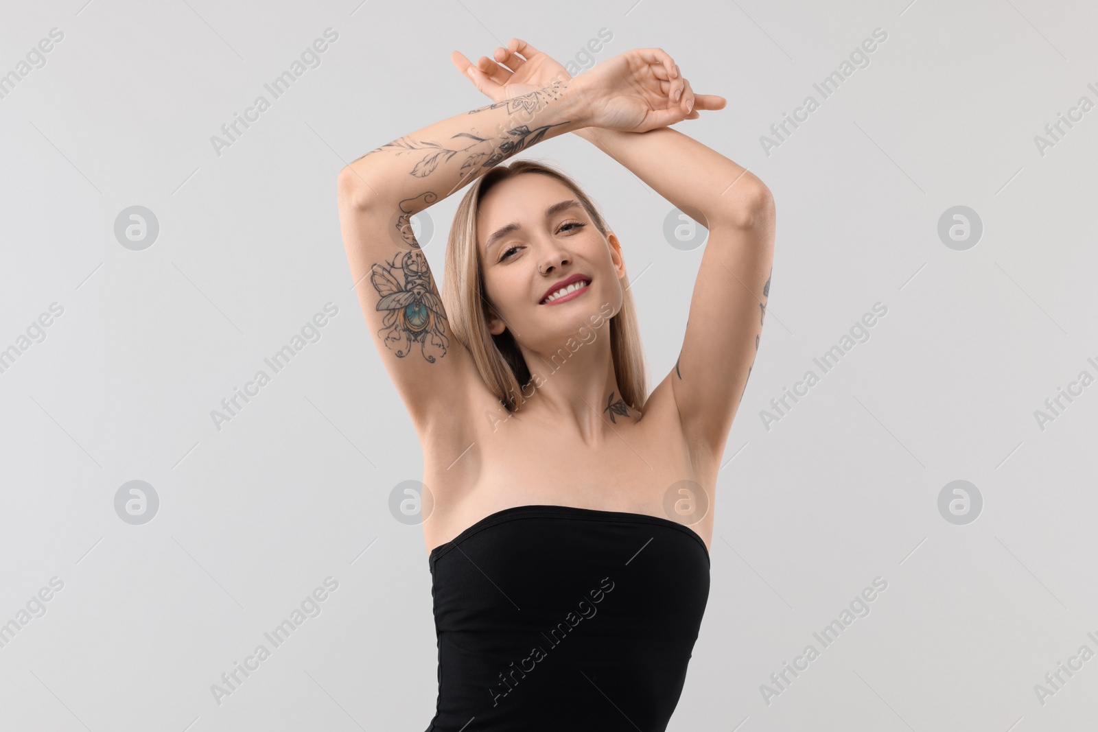 Photo of Portrait of beautiful tattooed woman on light background